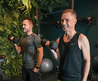 Dennis trainiert zusammen mit seinem Kunden den Biceps. Er nutzt dafür die Kurzhantel